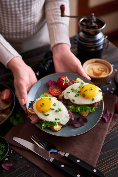 istock Tasty breakfast - fried egg toasts, bacon, tomatoes on wooden kitchen table 1473377769