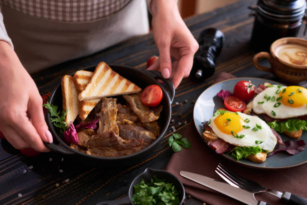 istock Tasty breakfast - fried egg toasts, bacon, tomatoes on wooden kitchen table 1473377770