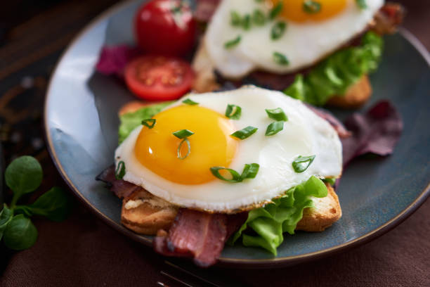 istock Tasty breakfast - fried egg toasts, bacon, tomatoes on wooden kitchen table 1473377781