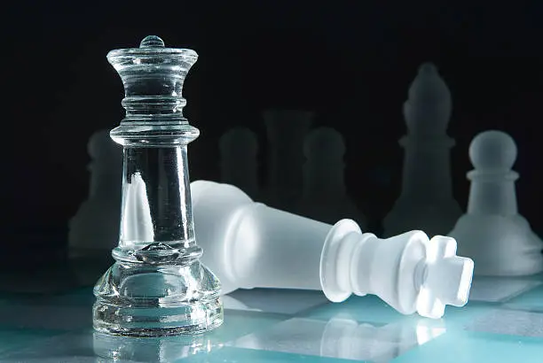 Glass chessmen on a smooth surface dark background