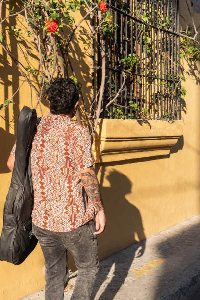 A musician with a guitar walks down a street