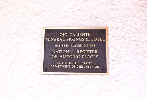 Ojo Caliente, NM: A bronze information plaque at the historic Hotel at Ojo Caliente, dating from 1917. Ojo Caliente is an ancient hot springs 50 miles north of Santa Fe.