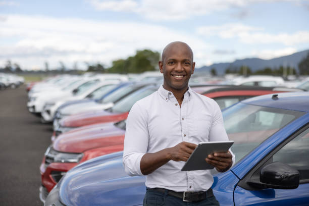 istock Happy salesman working at a car dealership using a tablet 1473399414