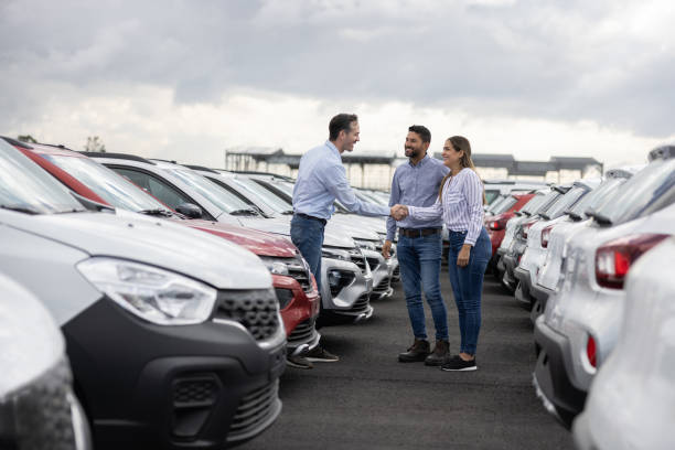 Couple handshaking with a car salesperson after buying a car stock photo