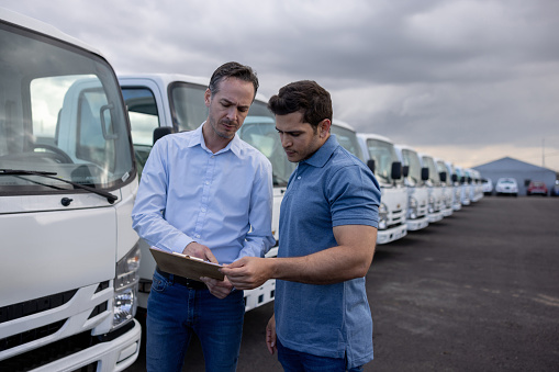 Latin American salesman showing trucks to a customer at the dealership - car ownership concepts