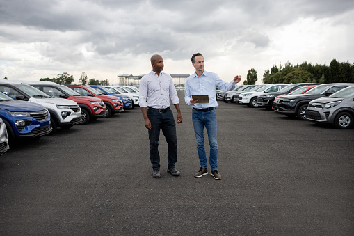 Latin American salesman talking to a client interested in buying a car at the dealership