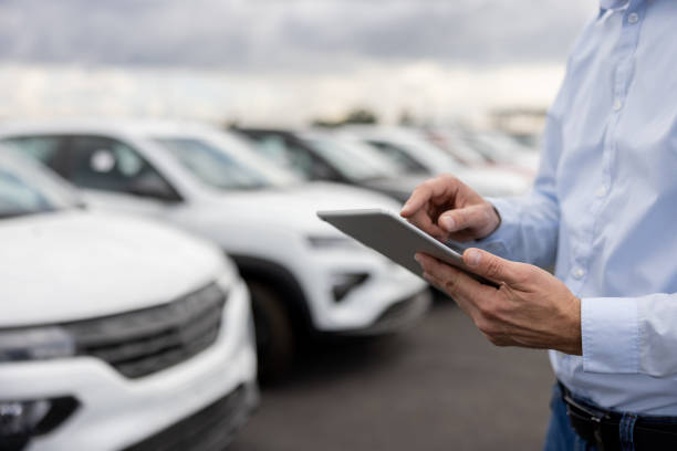 Close-up on a car salesperson using a tablet computer Close-up on a car salesperson using a tablet computer at the car dealership car salesperson stock pictures, royalty-free photos & images