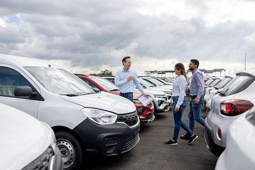 Latin American salesman showing cars to a couple at the dealership - buying a car concepts