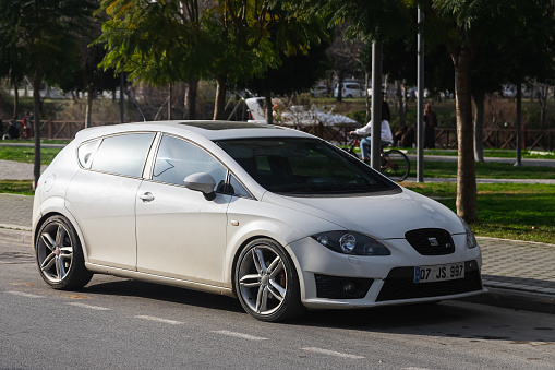 Side, Turkey -January 27, 2023:   white Seat Leon  is parked  on the street on a warm summer day against the backdrop of a shops