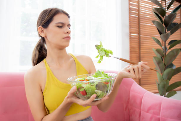 istock Young caucasian woman sitting on sofa eating vegetable salad while feeling dislike and expression disgusted, woman emotion frustrated with anorexia vegetarian and hate, nutrition food concept. 1473405028