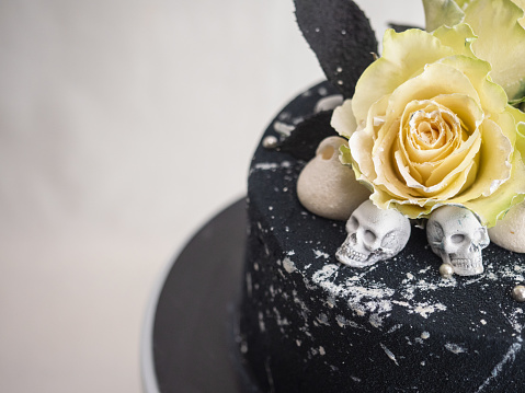 black airbrush painted frosted icing cake on top two real roses silver sprayed and edible chocolate skull