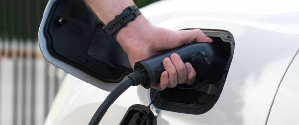 istock Closeup focus hand insert EV charger to progressive electric rechargeable car. 1473407599