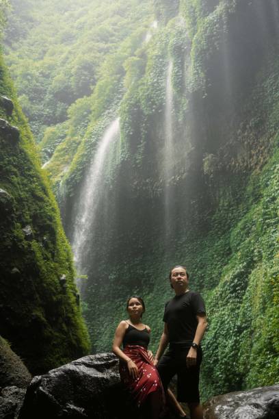 азиатская пара под тропическим водопадом мадакарипура - bromo crater стоковые фото и изображения