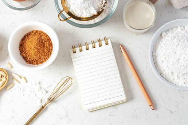istock Notebook and pen with baking ingredients, flour, brown sugar, milk on marble table 1473415948