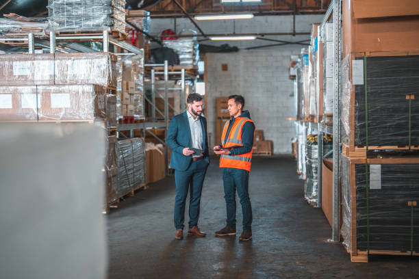 istock Caucasian And Asian Men Standing In A Warehouse, Discussing While In A Meeting 1473416769