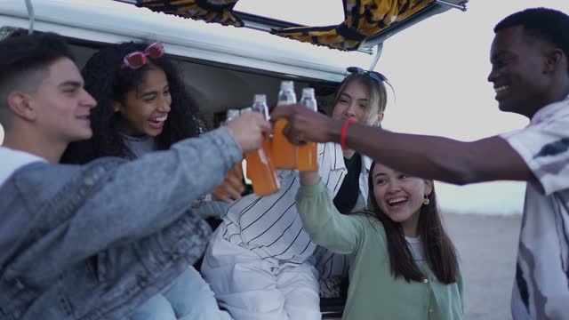 Group of young friends having a toast on a road trip with retro mini van transport