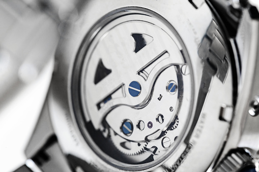 Movement of automatic mechanical wrist watch is behind transparent back case, close-up photo