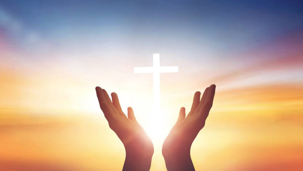istock Human hands open palm up worship god on Sunset background with cross on white 1473418463