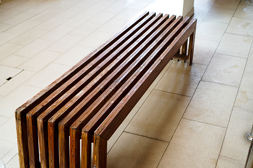 The picture shows a long wooden changing chair located at the edge of an indoor swimming pool.