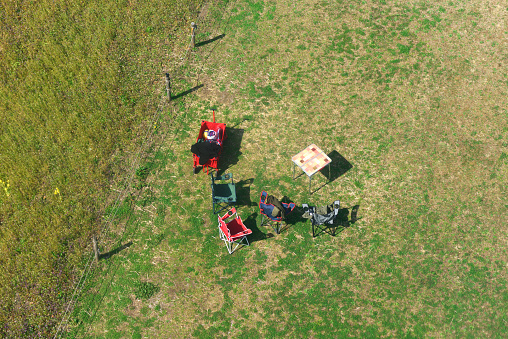 Aerial view of empty empty picnic table and chairs in sunny day.