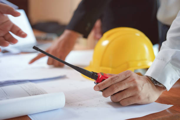 istock Team of Engineer or technician holding walkie talkie and planning about building plan with blueprint and construction tools on conference table at construction site. 1473424440