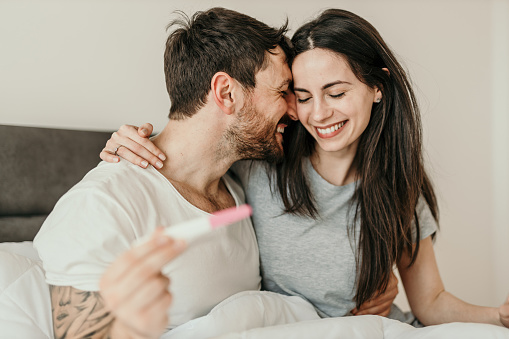 Cropped shot of an affectionate young couple looking excited while looking at a pregnancy test in their bedroom at home