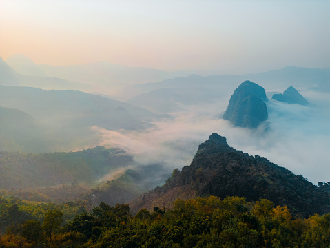 Scenic aerial view of karst mountains in clouds at sunrise