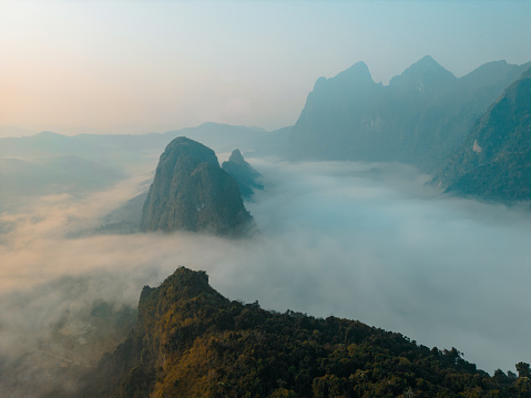 Scenic aerial view of karst mountains in clouds at sunrise