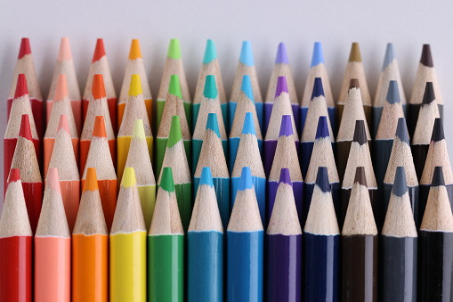 Set of multicolored pencils lying on white table in row. Creativity variou of possibilities and play of imagination and fantasy make the world bright and impressive
