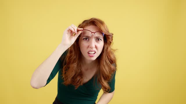 Redheaded woman with glasses staring at the camera in disbelief