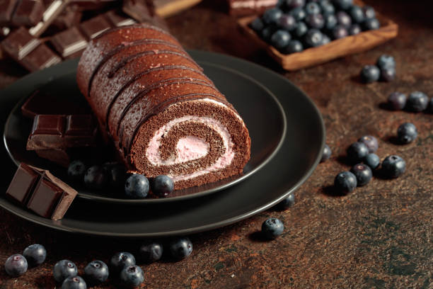 Chocolate roll cake with blueberries and a broken chocolate bar.