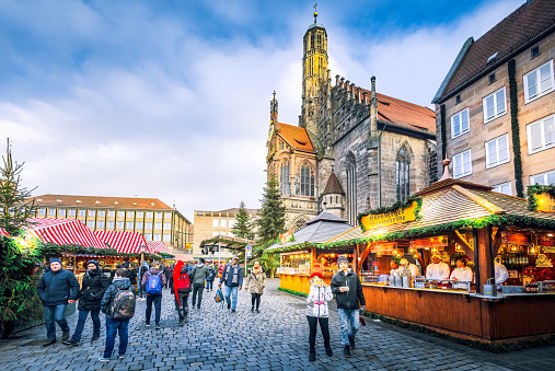 Nuremberg, Germany - November 2022. Tourists in Christkindlesmarkt, one of the oldest Christmas markets, famous Bavaria touristic background.