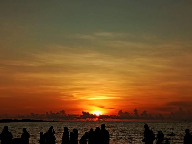 istock Sunset Beach family sky water orange clouds 1473432734