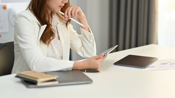 istock Concentred milennila female corporate CEO in elegant suit using digital tablet at her workplace. 1473434816