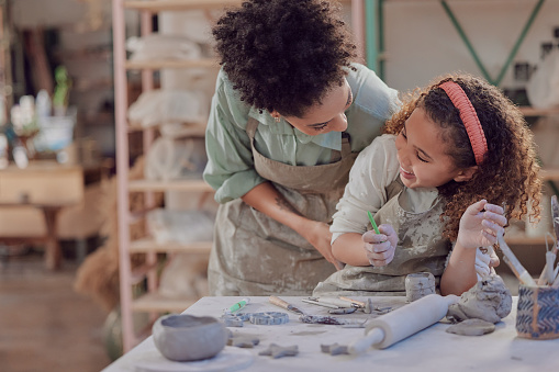 Pottery, black woman and girl have fun in sculpting class, learning and laugh, playful and creativity in art lesson. Playful, help and mother with kid, creative in ceramic workshop and clay handcraft