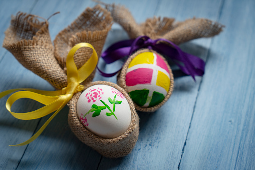 Tender colored easter eggs decorated in a nest of straw on a white wooden table