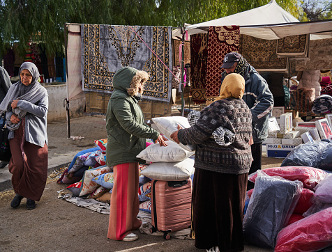 Sousse, Tunisia, January 22, 2023: Customers examine the goods at a stall selling cushions, bedding and carpets at the local market in Sousse