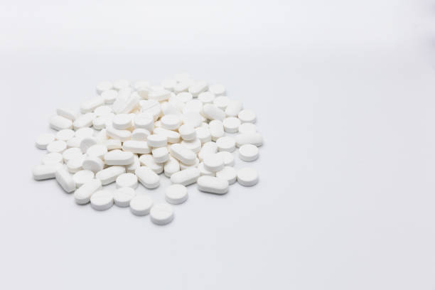 istock A pile of white circular, oval tablet pills stacked on a white background 1473436345