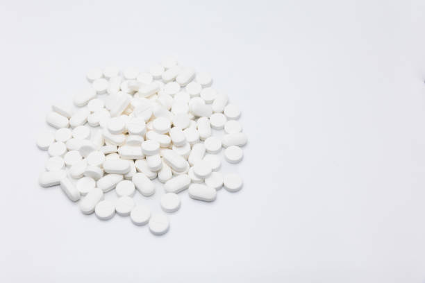istock A pile of white circular, oval tablet pills stacked on a white background 1473436415