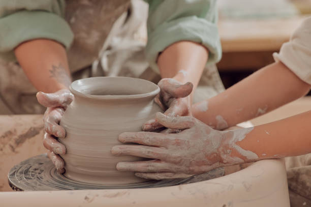 istock Closeup, hands and pottery class for creativity, learning and workshop for clay art, handicraft and design. Zoom, people and students with ceramic, spinning wheel and creative with shape and teaching 1473437288