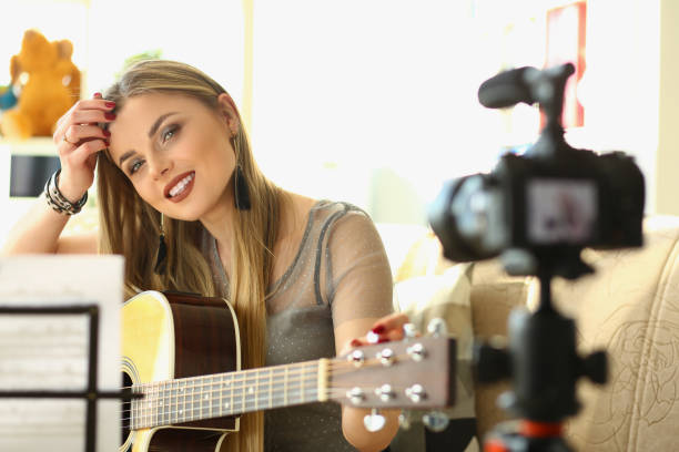 istock Woman on couch records online guitar lessons 1473437537
