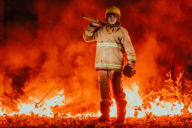 istock Firefighter at job. Firefighter in dangerous forest areas surrounded by strong fire. Concept of the work of the fire service 1473439933