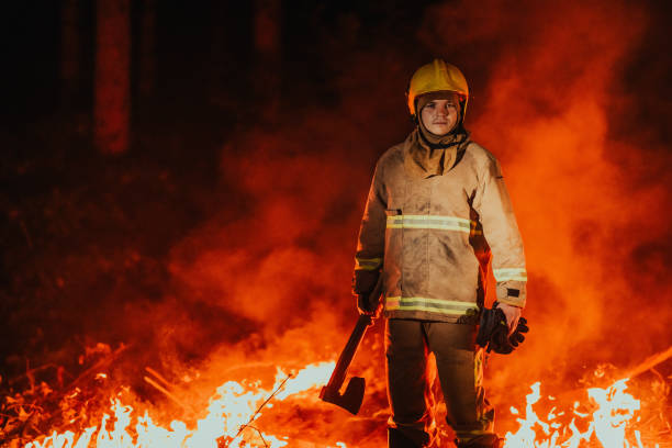 istock Firefighter at job. Firefighter in dangerous forest areas surrounded by strong fire. Concept of the work of the fire service 1473439967