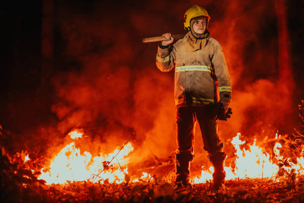 istock Firefighter at job. Firefighter in dangerous forest areas surrounded by strong fire. Concept of the work of the fire service 1473440103