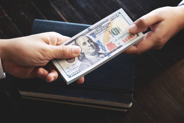 istock Business people giving dollar bribery for corruption contract. 1473442280
