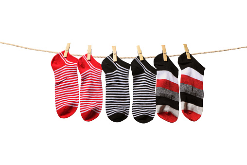 Clean washed striped socks hanging on rope isolated on white background. Clothesline with red, grey and white socks