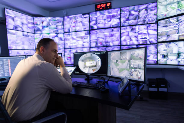 istock Man working in surveillance room and looking at monitors 1473443409