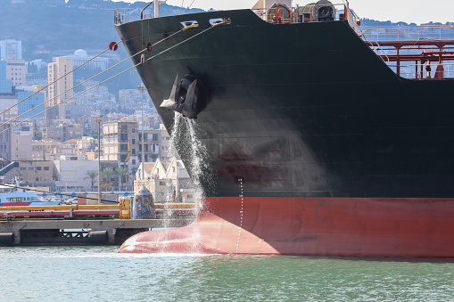 Large anchored cargo ship discharging ballast water.