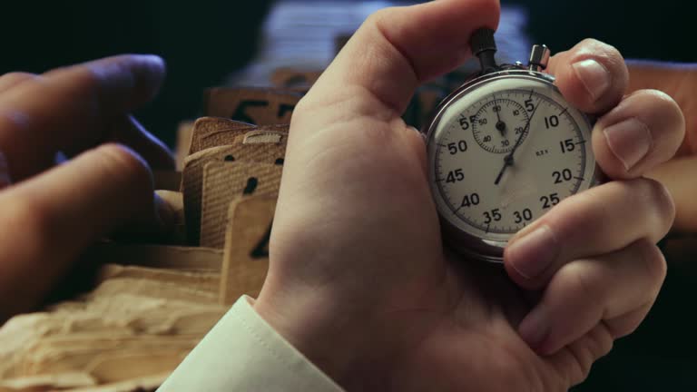 A man searching information in an old card catalogue and stopwatch in a hand