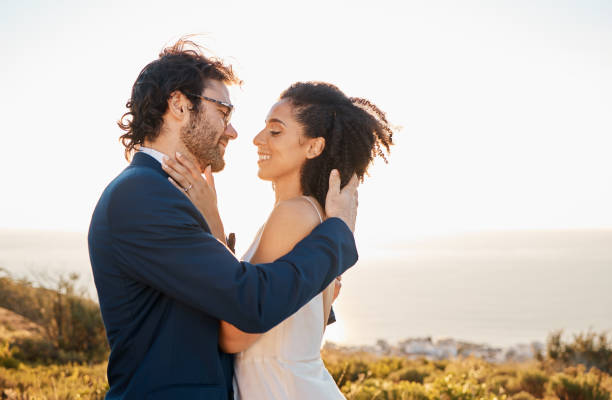istock Love, wedding and bride with groom on mountain for marriage ceremony, commitment and celebration. Romance, happiness and interracial couple bonding, kiss and smile with ocean, nature and outdoors 1473449378